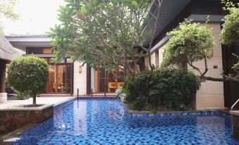 a beautiful blue mosaic swimming pool in a courtyard , surrounded by lush greenery and a wooden house at Sanya Haitang Bay Island Villa (International Duty Free City Branch)
