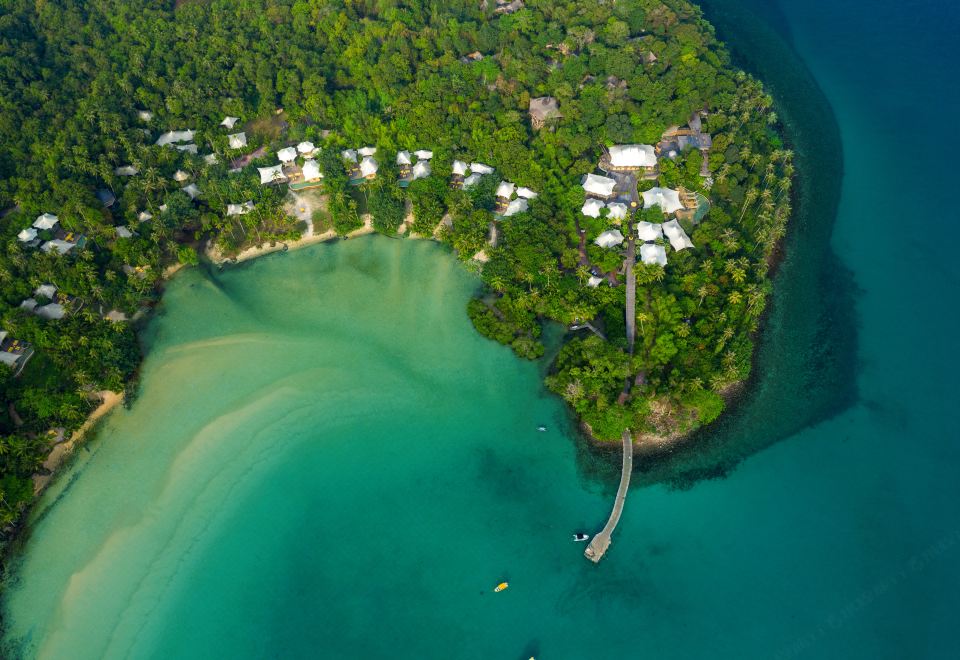 an aerial view of a tropical island with lush greenery , clear blue water , and white buildings at Soneva Kiri