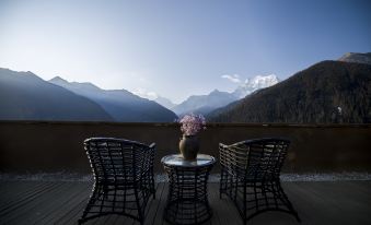 On an overcast day in Japan, there is a balcony with chairs and a table that overlooks the mountains at Hotel Blanche