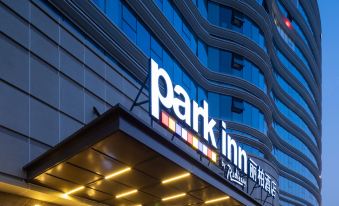 At night, the front entrance of a hotel is adorned with a sign in Chinese and Japanese at Park Inn by Radisson Beijing Tongzhou Universal Resort