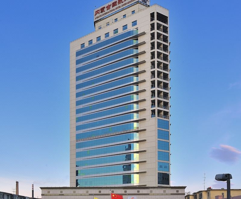 a tall , modern building with a red sign on the top floor and other businesses below it at Phoenix Hotel