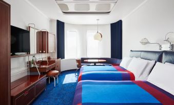 a modern hotel room with two beds , a desk , and a window , all decorated in blue and white at The Standard London