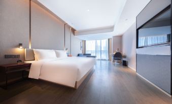 A modern bedroom with a large bed and white chairs in the middle at Atour Hotel Shunde Happy Coast Foshan