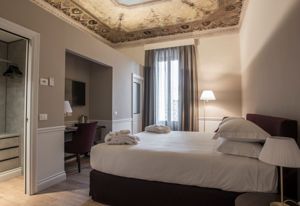 a large bed with white linens is in a room with wooden floors and a high ceiling at Palazzo Castri 1874 Hotel & Spa