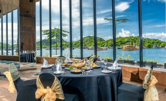 a table with a black cloth and gold bow is set up in front of a large window overlooking the water at Meruorah Komodo Labuan Bajo
