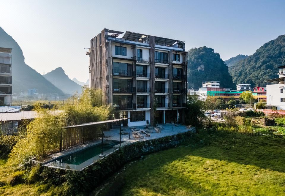 The pool at the hotel offers a picturesque view of mountains in the background with clouds above at Yangshuo Sudder Street Guesthouse