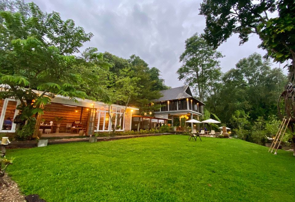 a large house surrounded by trees and grass , with several chairs and tables placed in the yard at Proud Phu Fah Hip & Green Resort