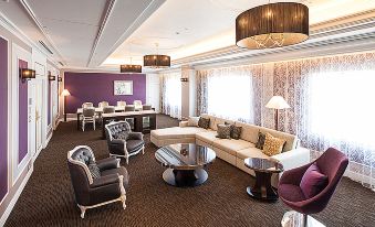 a modern living room with white couches , a wooden coffee table , and large windows , decorated with purple walls and gold accents at Nagoya Tokyu Hotel