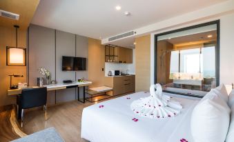 a modern bedroom with a white bed , wooden flooring , and a large window offering views of the city at Arize Hotel Sri Racha