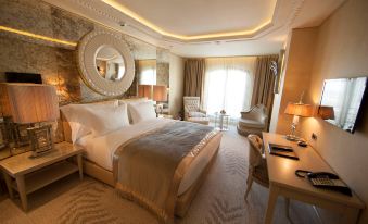 a luxurious hotel room with a large bed , a desk , and a mirror on the wall at Wyndham Grand Istanbul Kalamış Marina Hotel