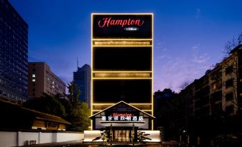 The exterior view of the hotel and restaurant at night is enhanced by a large sign on top at Hampton by Hilton