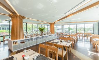 a large dining room with wooden tables and chairs arranged for a group of people to enjoy a meal together at Na Tree Tara Riverside Resort Amphawa Damnoensaduak