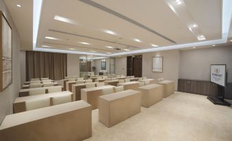 a large , empty conference room with beige walls and chairs arranged in rows , under a high ceiling with recessed lighting at Somerset Grand Central Dalian