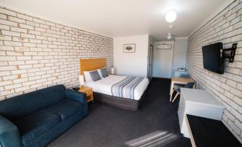 a modern hotel room with brick walls , white furniture , and a bed with blue bedding at The Heritage Bendigo