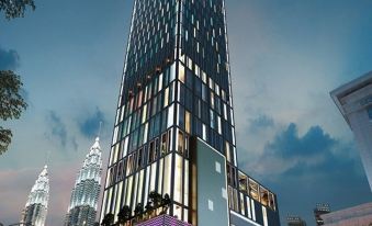A rendering depicts a new skyscraper being built next to an existing one, illuminated at night at Tropicana the Residences KLCC by Luxury Suites
