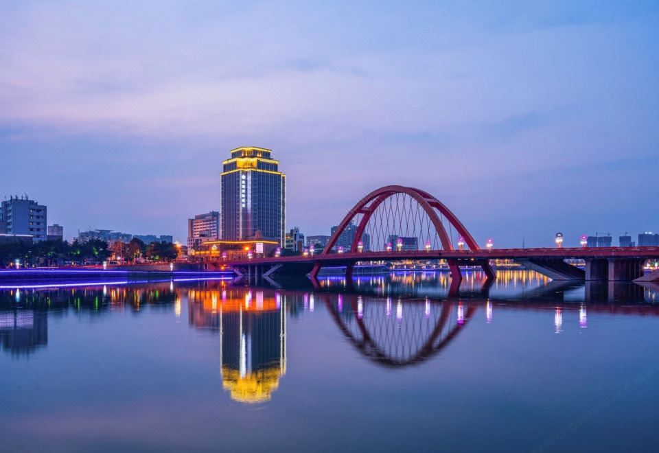 A city is reflected in the water at night, with buildings alongside it at Jinghu Hotel