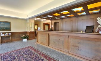 a hotel lobby with a wooden reception desk and a large painting on the wall at Best Western Titian Inn Hotel Venice Airport