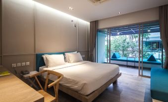 a modern hotel room with a large bed , desk , and sliding glass door leading to a balcony at Bann Pantai Resort