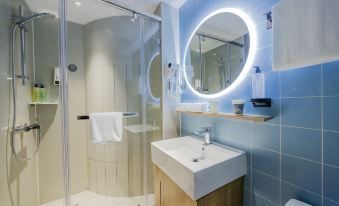 The bathroom features white and blue tiled walls, a round mirror above the sink, and a shower area at Neo Shanghai Nanjing Road Pedestrian Street Huanghe Road Store