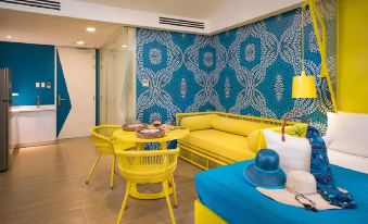 a brightly colored living room with a blue and yellow couch , a dining table , and chairs at Astoria Palawan