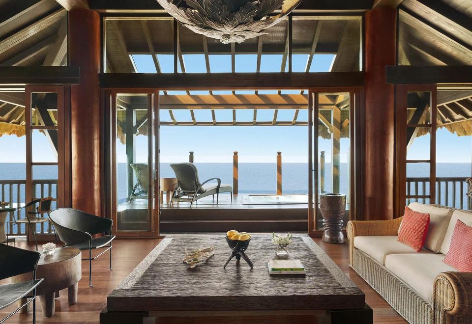 a luxurious living room with a large window offering an ocean view , featuring a wooden dining table and a potted plant at Shangri-La Boracay