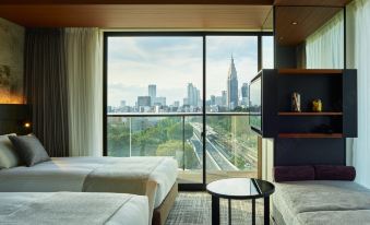 a hotel room with two beds , a table , and a window offering a view of the city at Mitsui Garden Hotel Jingugaien Tokyo Premier