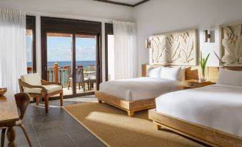 a hotel room with two twin beds , a chair , and a sliding glass door leading to a balcony at Zemi Beach House, LXR Hotels & Resorts