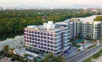 a large white building with purple accents is surrounded by trees and other buildings in an urban setting at Fortune Saeng Chan Beach Hotel Rayong