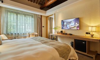 The bedroom features a large bed and a wall-mounted TV, with an open doorway nearby at Yiman Hotel (Suzhou Pingjiang Road Scenic Area)