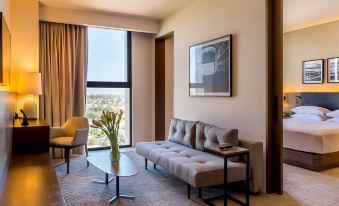 a modern living room with a gray sofa , white coffee table , and large window offering views of the city at Hyatt Regency Andares Guadalajara