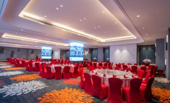 A ballroom is arranged for an event, with tables and chairs positioned in the center on a red floor at New Joyful Hotel