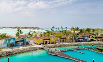a tropical resort with colorful buildings and palm trees , situated near a clear blue sea at Hard Rock Hotel Maldives
