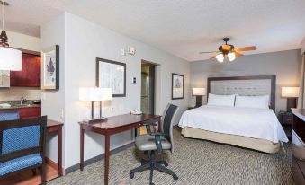 a hotel room with a bed , desk , and chair , along with other furniture and decorations at Homewood Suites by Hilton Bloomington