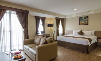 a modern hotel room with a large bed , couch , and window , along with various furniture and decorations at Hotel Horison Grand Serpong