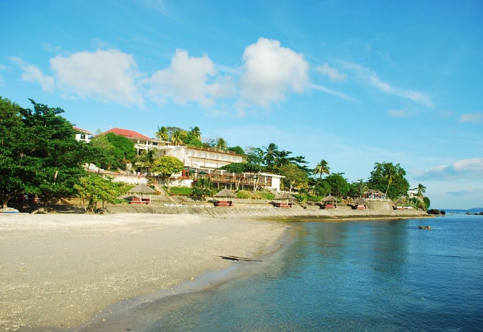 a beachfront property with a row of houses and palm trees , situated near a calm blue ocean at Almont Beach Resort