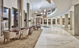 a modern , well - lit hotel lobby with marble floors and chairs arranged around a central area at DoubleTree by Hilton Malta
