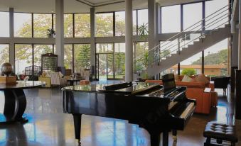 a large room with a grand piano in the center , surrounded by chairs and couches at Haile Resort Hawassa