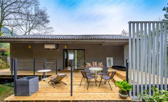 A large sliding glass surrounds a wooden deck on the patio, which is furnished with chairs and a table at Little Forest Guesthouse