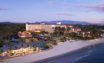 a large hotel with a beach and golf course in the foreground , surrounded by palm trees and mountains at Dusit Thani Hua Hin