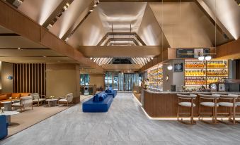 The large building features wood paneled ceilings on both sides, housing a lobby and bar at Crystal Orange Shenzhen Nanshan Science and Technology Park Hotel