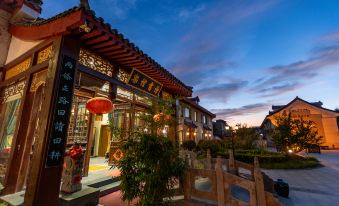 At night, an oriental-style building stands in front of a restaurant entrance, while a modern architectural structure serves as the backdrop, complemented by trees and streetlights at Fuzi Binshe Family Education Culture Boutique Hotel