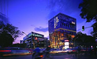 There is a large building with numerous windows and cars on the street at night in front at CITIGO hotel, Sanlitun, Beijing