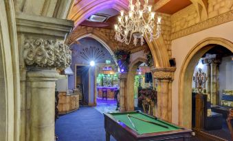 a billiards table is in the middle of an old - fashioned room with a chandelier hanging above it at Empire Hotel
