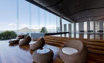 a modern lounge area with a large window , wooden flooring , and various seating options arranged in front of the space at The Lake View Toya Nonokaze Resort