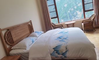 The bedroom features a double bed and a large window with a view of the mountainous region at Tina's Youth Hostel