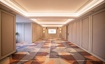 There is an empty room next to a long hallway with carpet on the floor and walls at Mercure Guangzhou Beijing Road Pedestrian Street Hotel