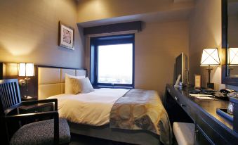 a hotel room with a bed , desk , and chair , as well as a window overlooking the city at La Vista Hakodate Bay