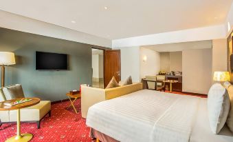 a modern hotel room with a large bed , couch , and tv , as well as a dining table and chairs at Swiss-Belhotel Bogor
