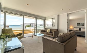 a modern living room with large windows , a couch , and chairs , offering a view of the ocean at Sacred Waters Taupo