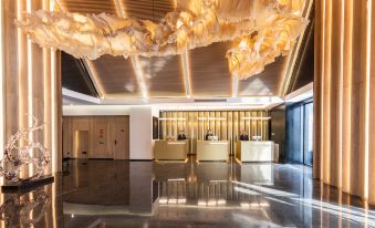 The lobby features a modern design with a prominent chandelier and an artistic ceiling at Atour S Hotel